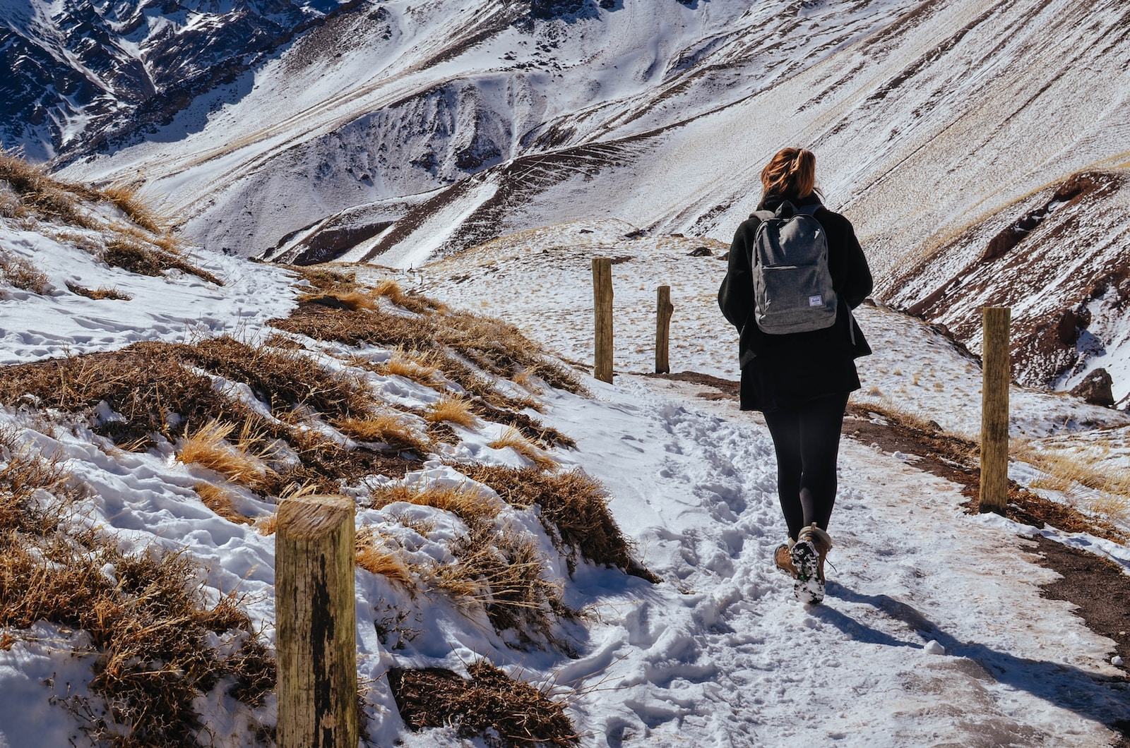 woman walking near mountain covered by snow during daytime